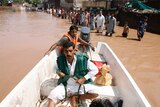 A rescue worker steers a a boat as flood victims wait for their turn in floodwaters, caused by heavy rain.