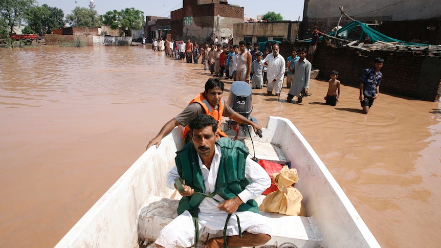 A rescue worker steers a a boat as flood victims wait for their turn in floodwaters, caused by heavy rain.