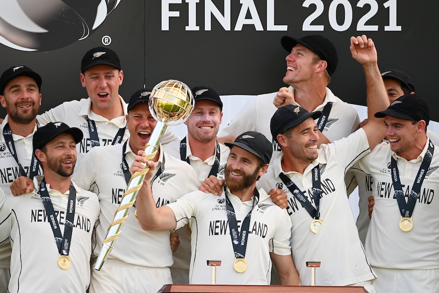Kane Williamson holds a gold mace in front of smiling teammates