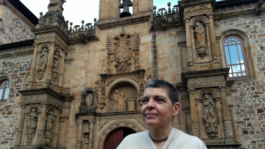 woman stands in front of sandstone building