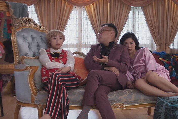 Colour mid-shot still of rapper and actor Awkwafina in a scene with Nico Santos and Constance Wu in 2018 film Crazy Rich Asians.