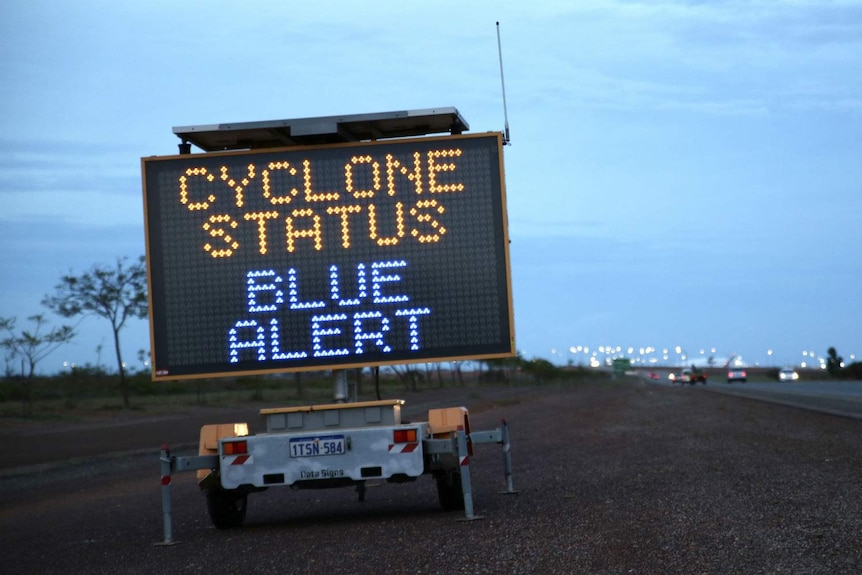 A transportable roadside electronic sign which reads "Cyclone Status Blue Alert".