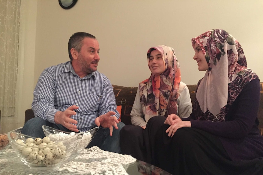 Islamic Council of Victoria executive director Nail Aykan sits in his lounge room with his daughters Nesibe and Merve.