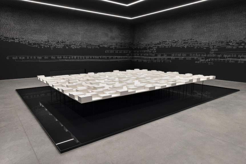 A large table covered with reams of documents sits above black reflective flooring in a room with black walls covered in chalk.