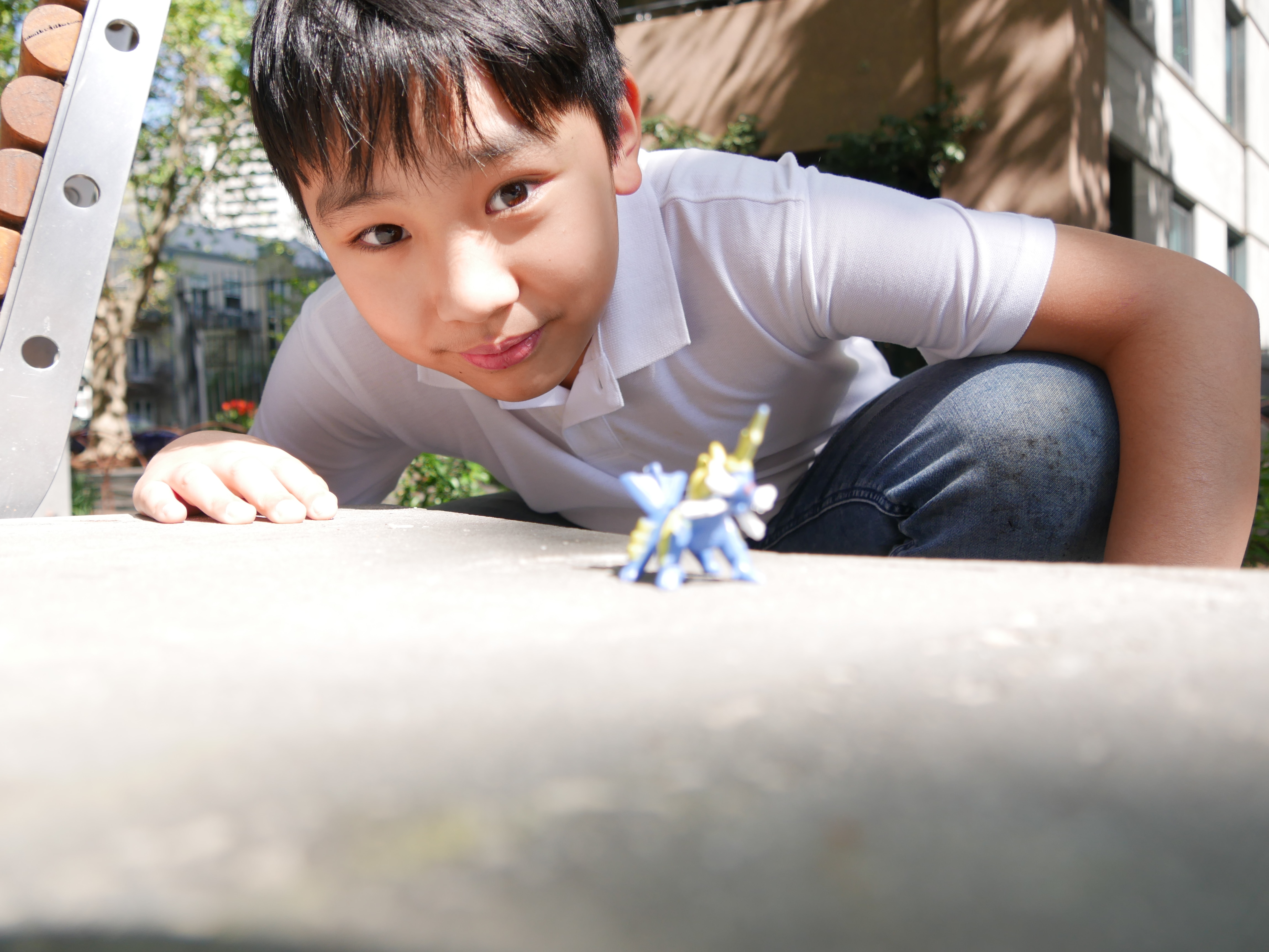 A boy crouched down near a toy figurine
