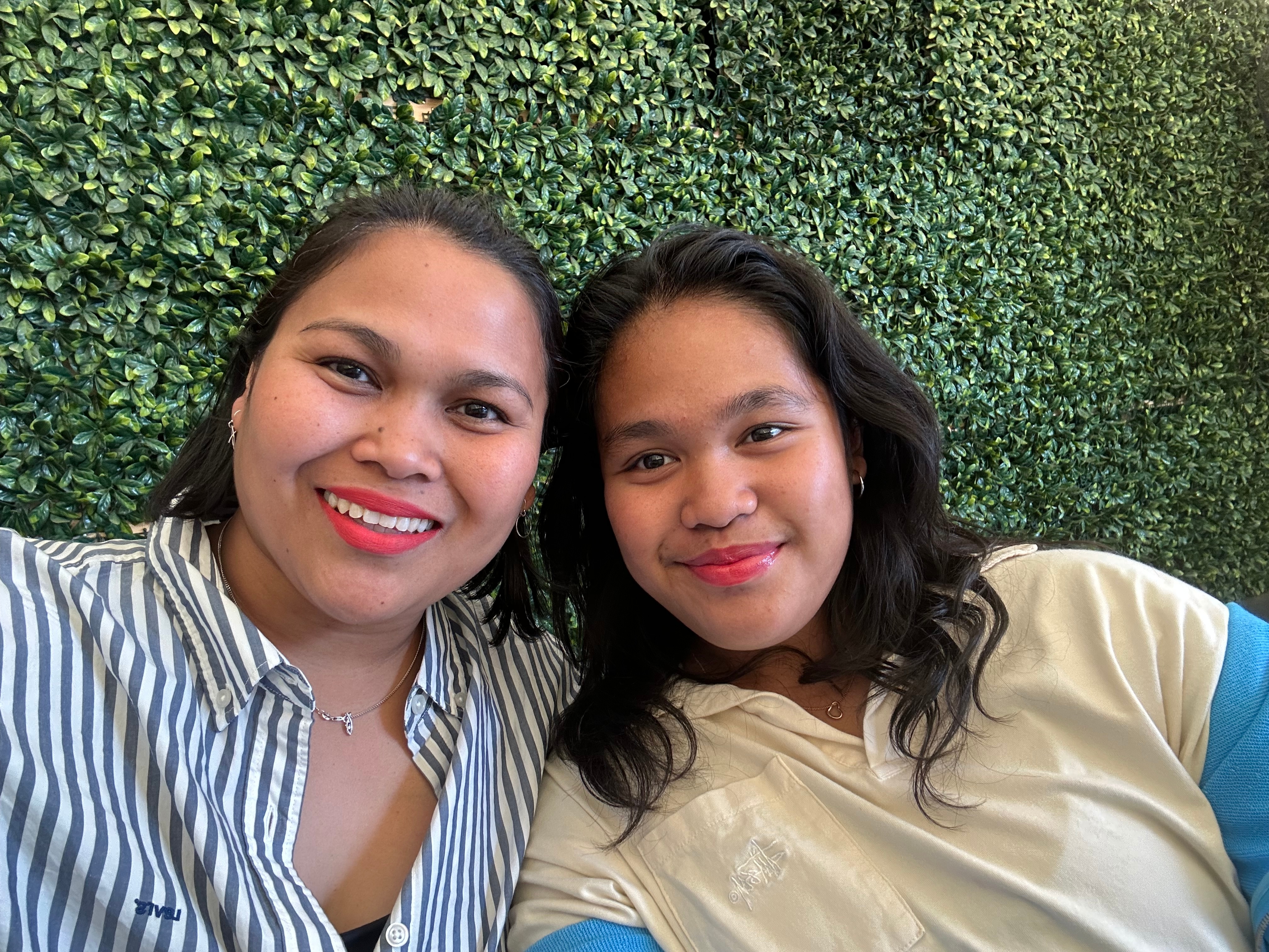 Woman and daughter smiling at camera with green background