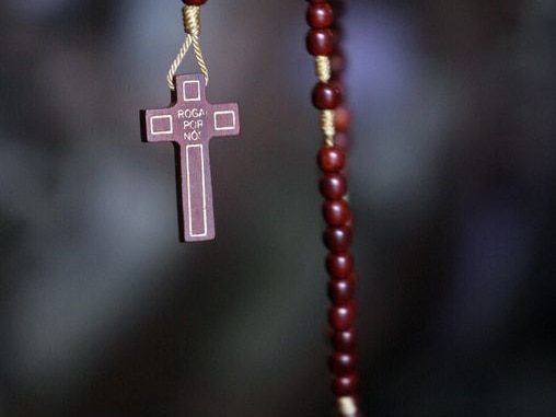 Hands holding a rosary with a crucifix