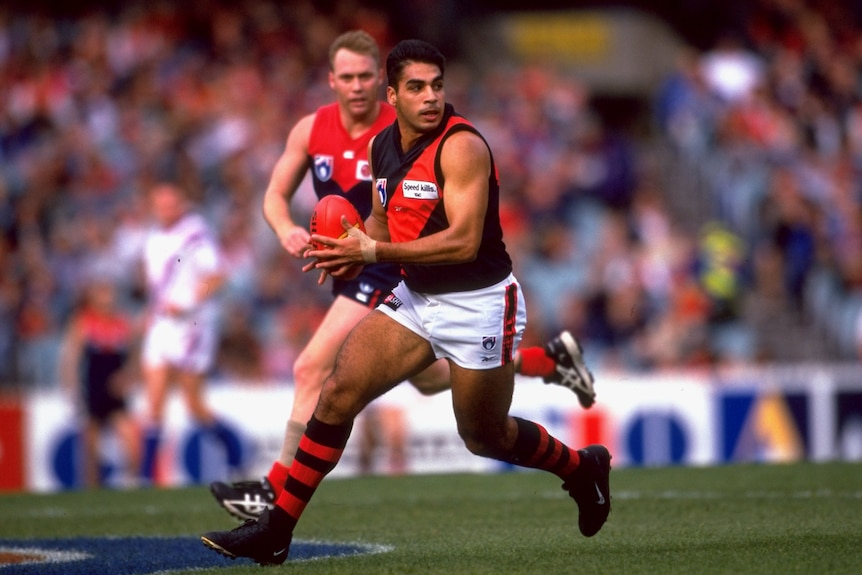 A man runs the ball during an AFL match