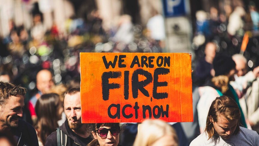 Protestors at climate rally holding sign saying we are on fire.