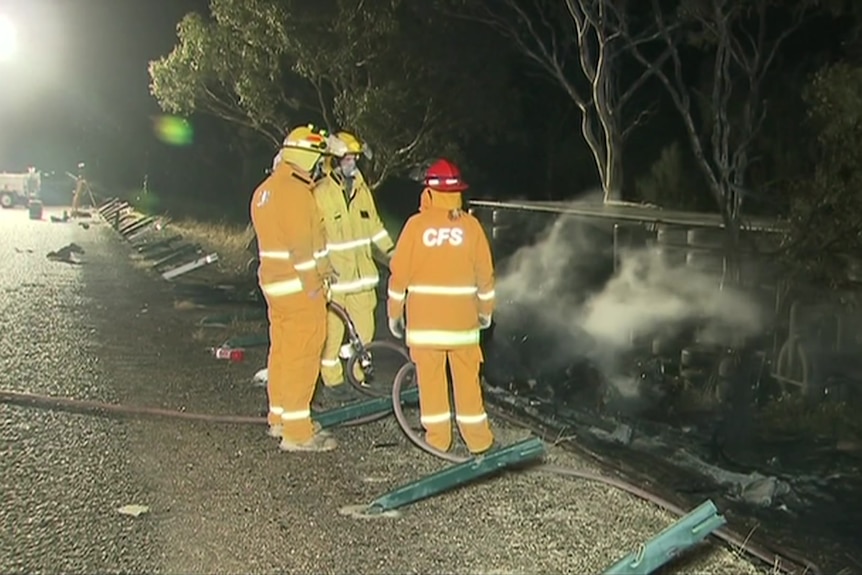 CFS volunteers stand near a smoking truck rolled on its side