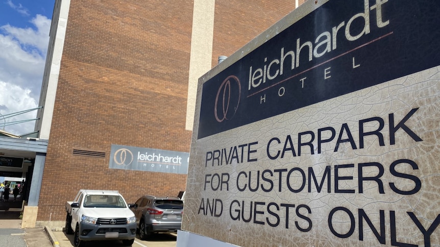 A photo of a car park sign with cars in background