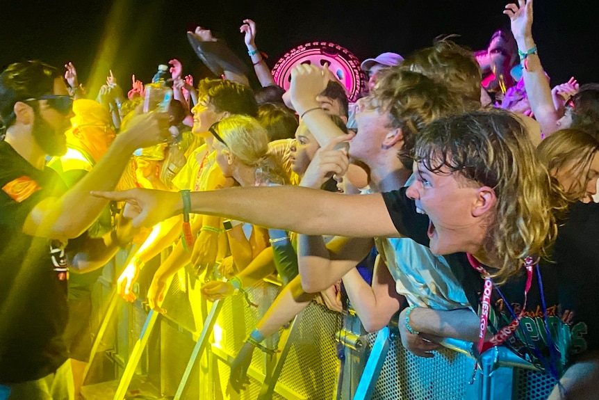 jeunes entassés sur la barrière de la scène lors d'un concert de musique