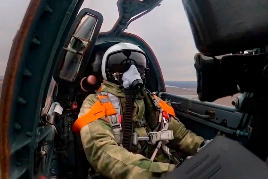Picture of a man in a military pilot gear inside a jet fighter 