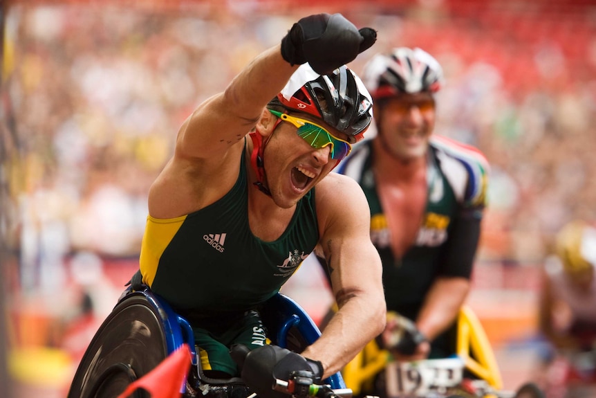 Kurt Fearnley raises his fist in celebration after a wheelchair race competing for Australia