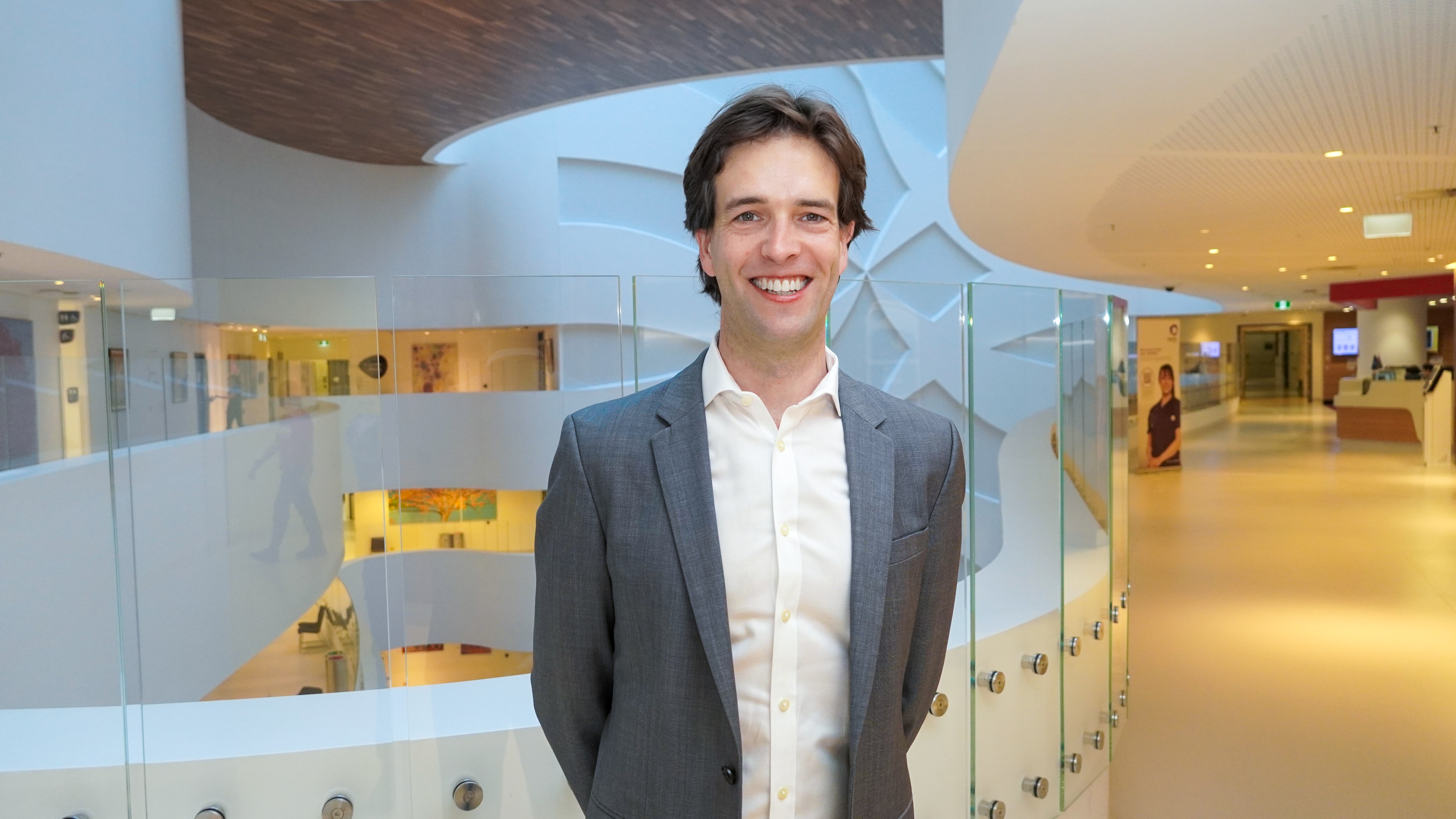 A man in a grey suit standing in a hospital.