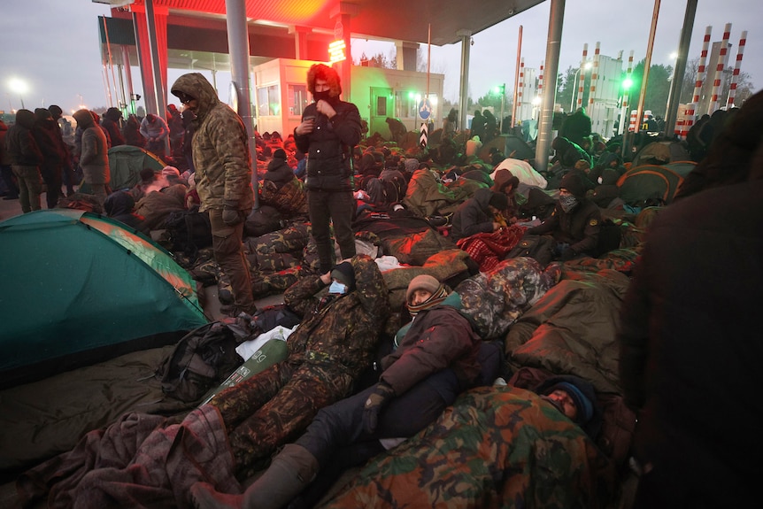 Le persone sono stese a terra e dormono all'aperto al confine 