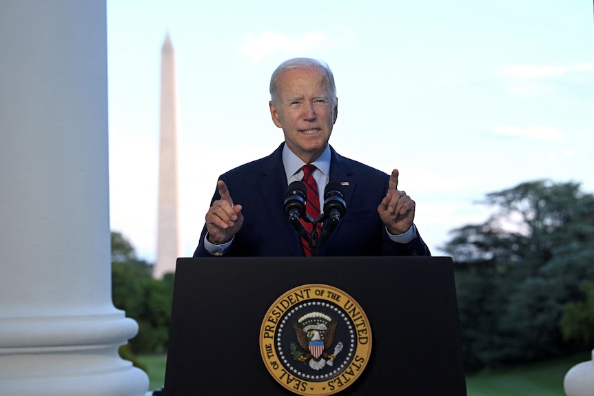 US President Joe Biden stands behind a lecturn.