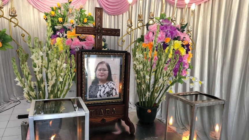 A framed photo of Martha Djumani surrounded by flowers and candles.
