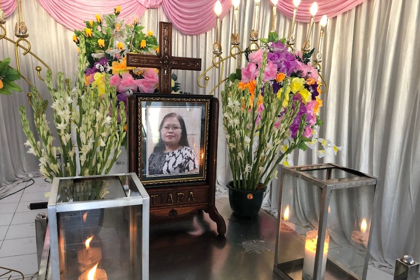 A framed photo of Martha Djumani surrounded by flowers and candles.