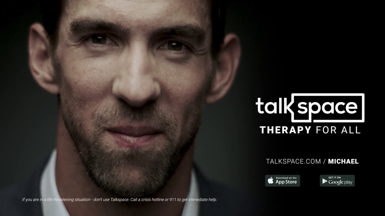 Michael Phelps looks at the camera next to a sign for Talkspace