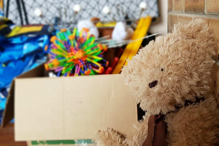A teddy bear and a box of toys in a children's room.