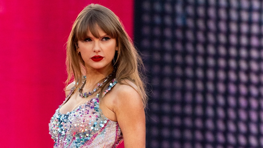 Close up of Taylor Swift looking serious on stage in sparkly bodysuit