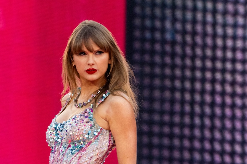 Close up of Taylor Swift looking serious on stage in sparkly bodysuit