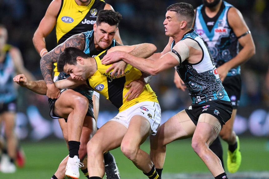 Trent Cotchin is tackled by Port Adelaide Power players.