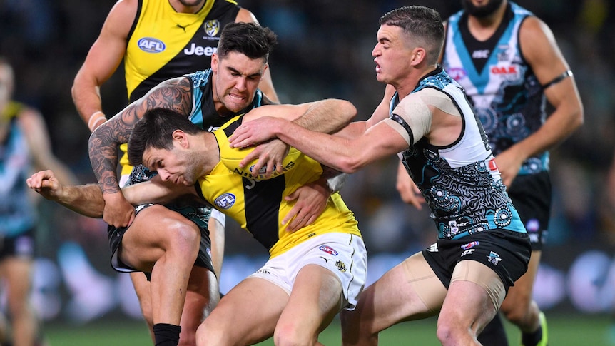Trent Cotchin is tackled by Port Adelaide Power players.