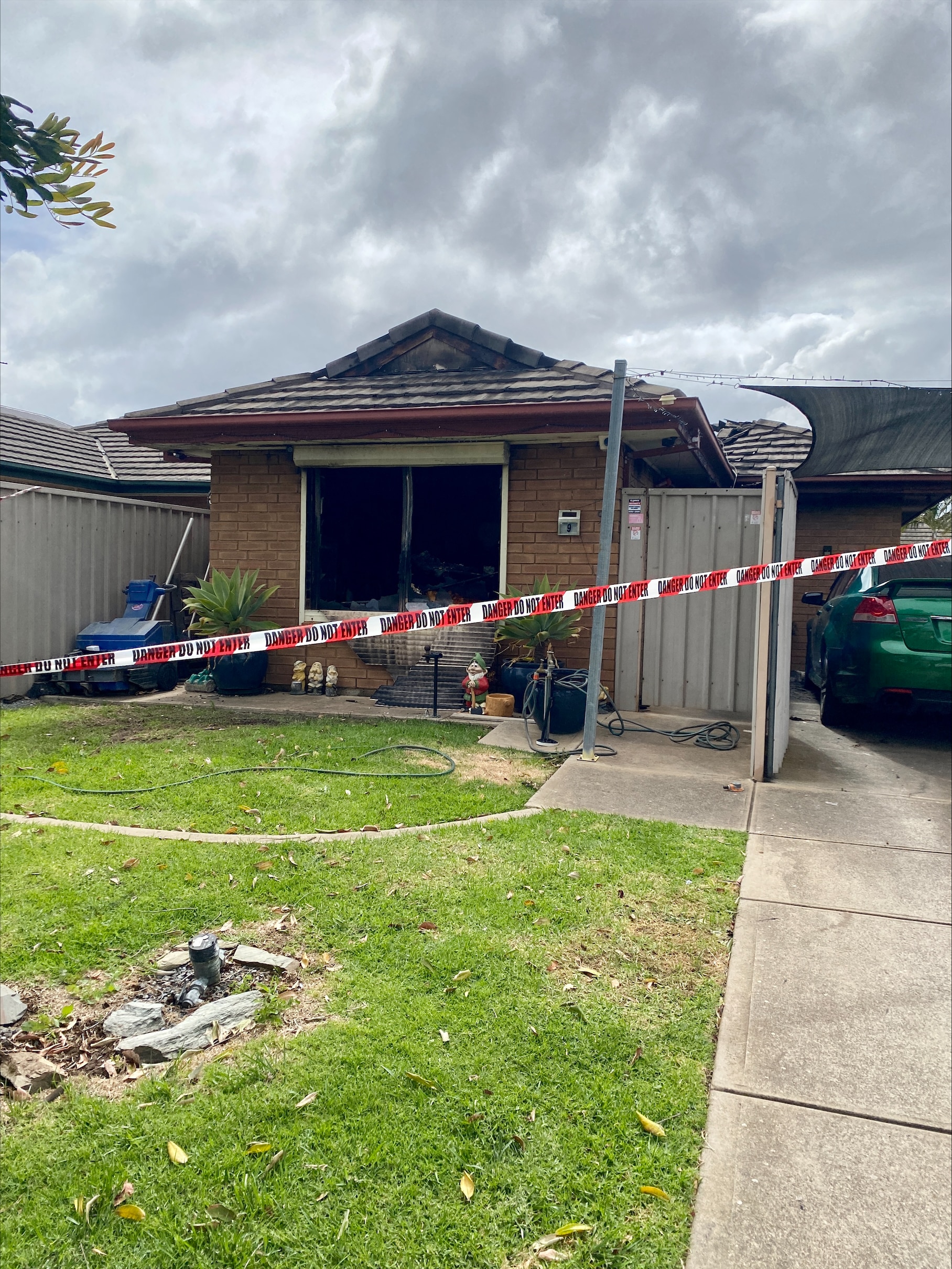 Police tape across the front of house that has been destroyed by fire