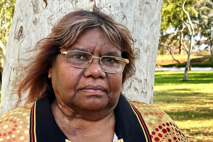 indigenous middle-aged woman wearing glassess and a yellow and red polo shirt