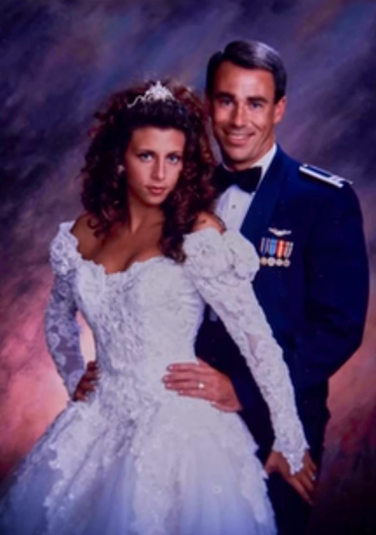 A wedding photo from the late 80s or early 90s of a serviceman in uniform and woman in a bridal dress posing for photo shoot.