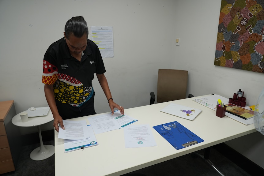 Indigenous woman looking at paperwork on a white table.
