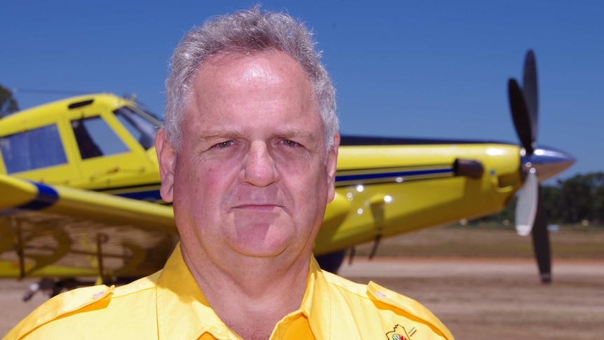 man stands in front of a yellow plane.