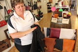 A woman in her shop holding a black piece of tanned kangaroo leather.