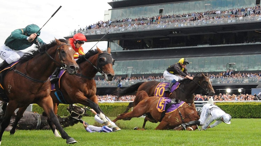 Two jockeys are thrown from their horses and hit the grass