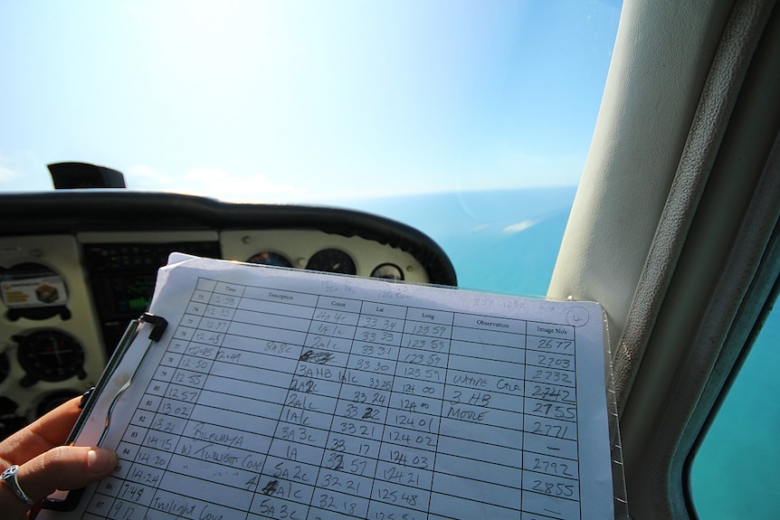 A person holding a log on a clipboard in a plane cockpit.