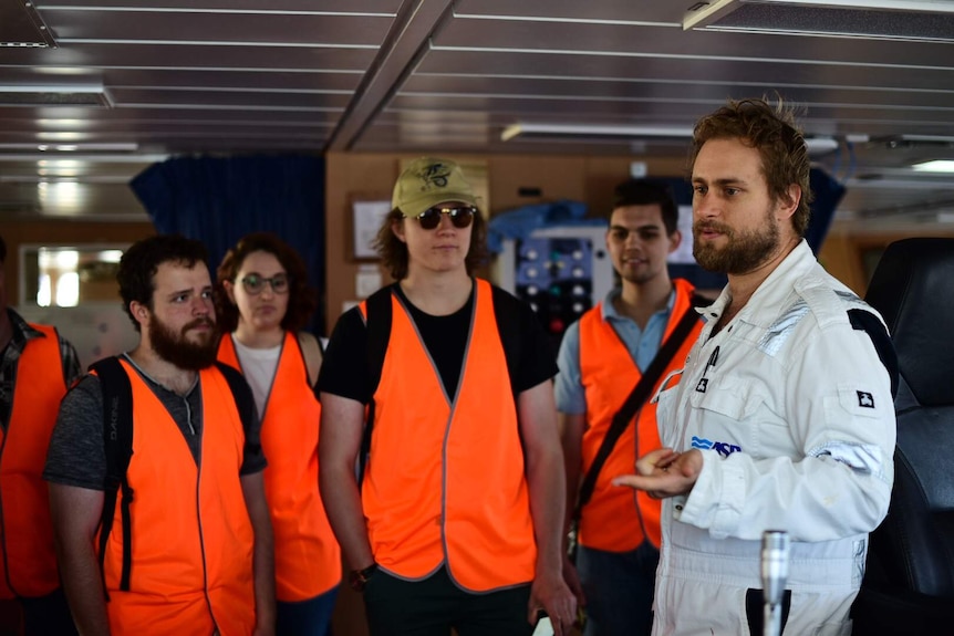 A scientist shows students around the RV Investigator