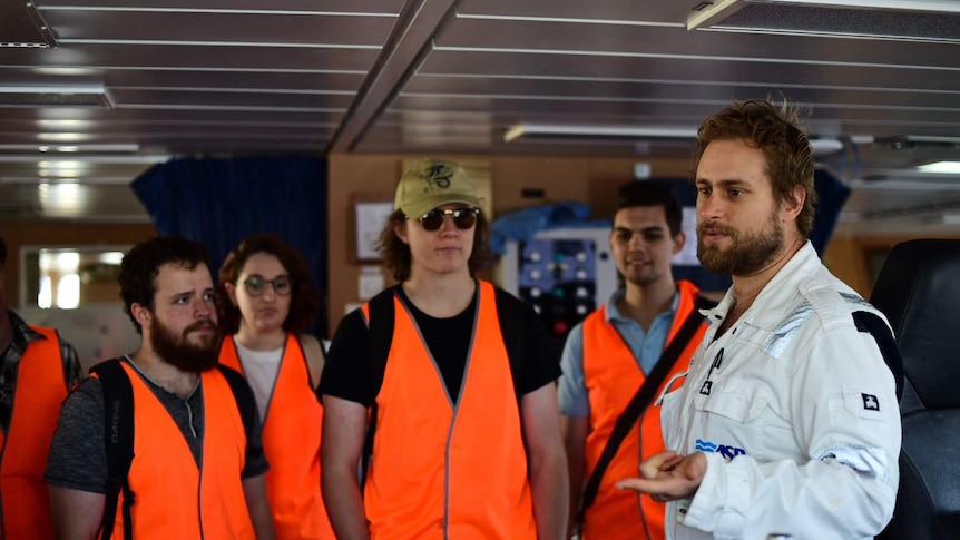 A scientist shows students around the RV Investigator