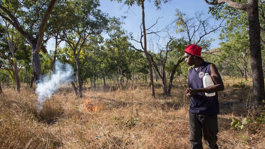 a man lighting a fire in scrub