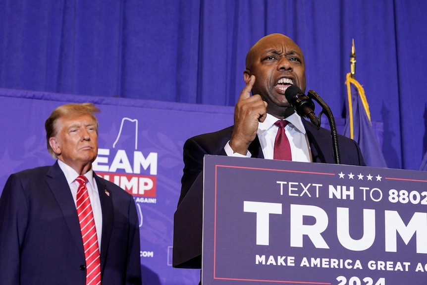 Tim Scott yells at a lectern while Trump stands behind him frowning
