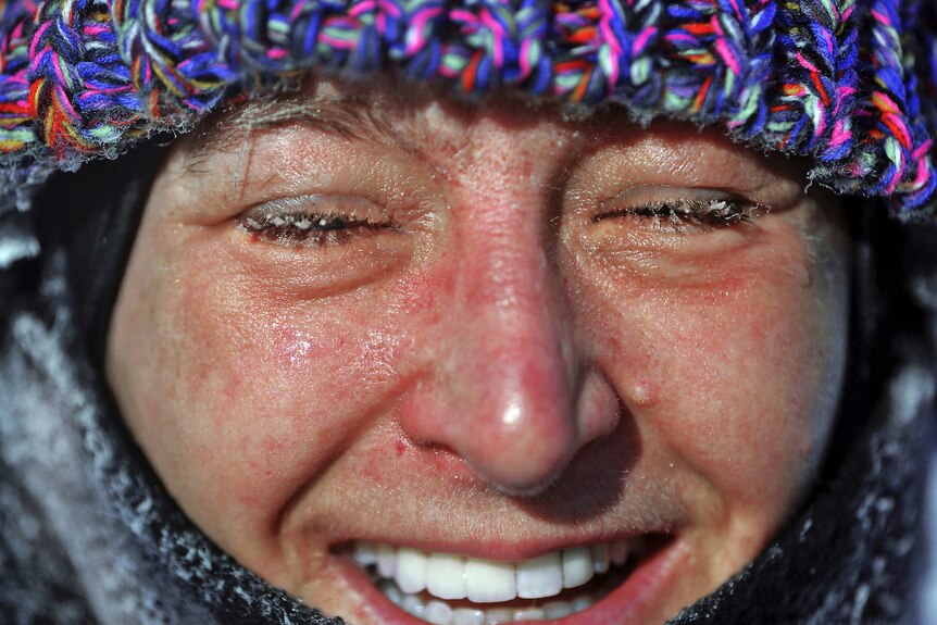 Close up of smiling woman with frozen eyelashes and red face