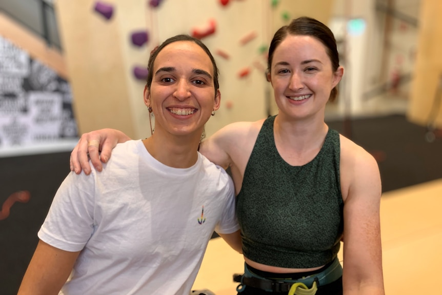 Sarah Larcombe and Araminta McLennan smile as they stand side by side in a climbing room.