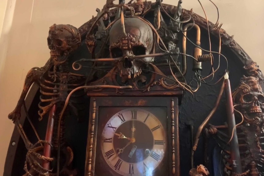 Artwork of antique roman numeral clock surrounded by fake skeleton, skull and copper wiring
