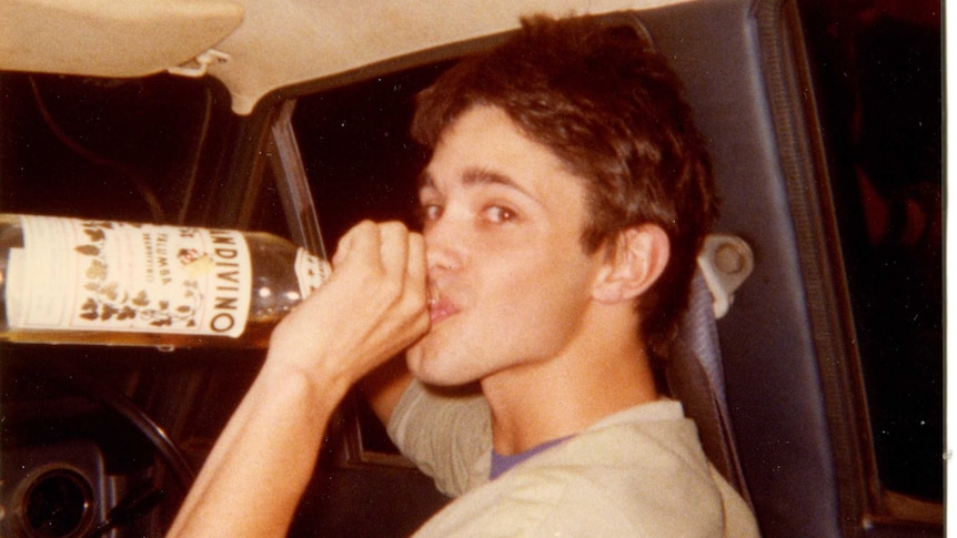 Andy Griffiths in the early 1980s sitting in a car taking a swig from a bottle