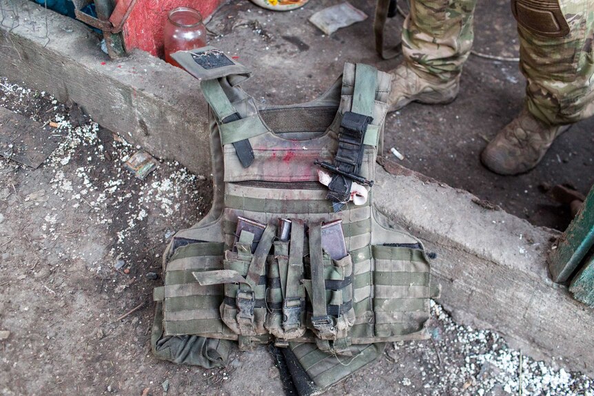 A bloodied bullet-proof vest on the ground.