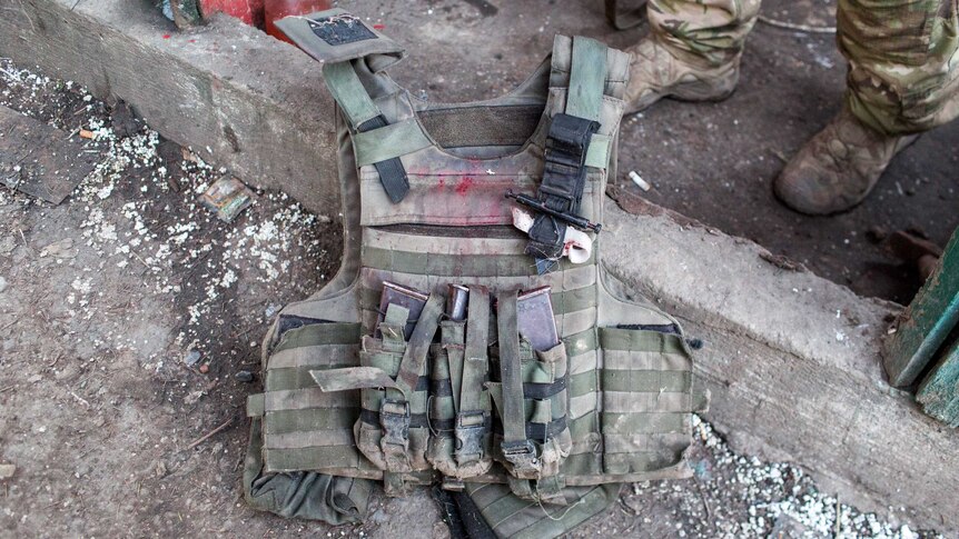 A bloodied bullet-proof vest on the ground.