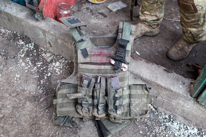 A bloodied bullet-proof vest on the ground.