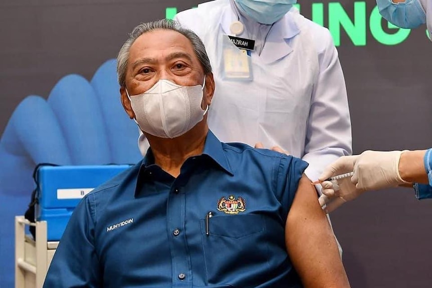 A man wears a face mask while receiving a COVID-19 shot