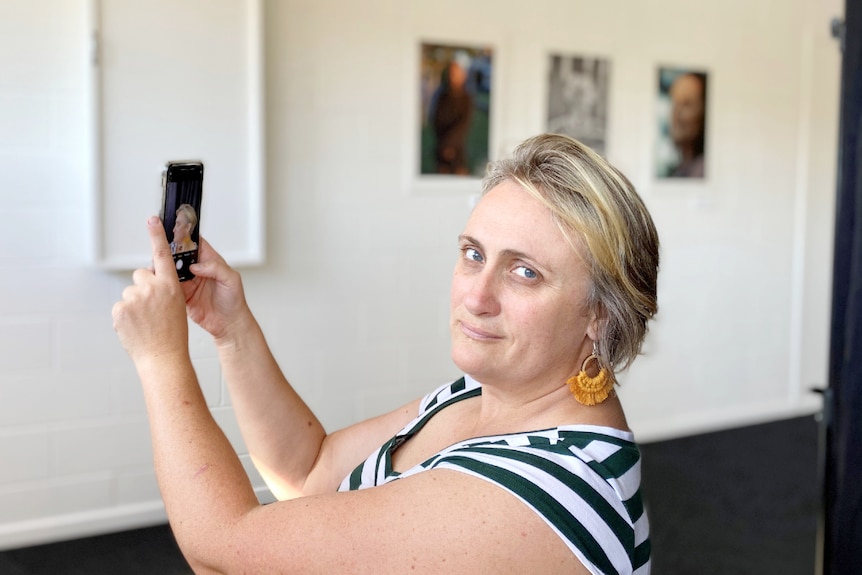 A woman looks at the camera while taking a selfie